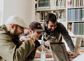 Image of young people collaborating on a set of computers.